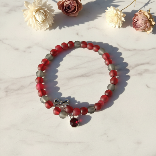 Frosted red and gray glass moon bead memory wire wrap bracelet with bow and red crystal charm on marble lifestyle