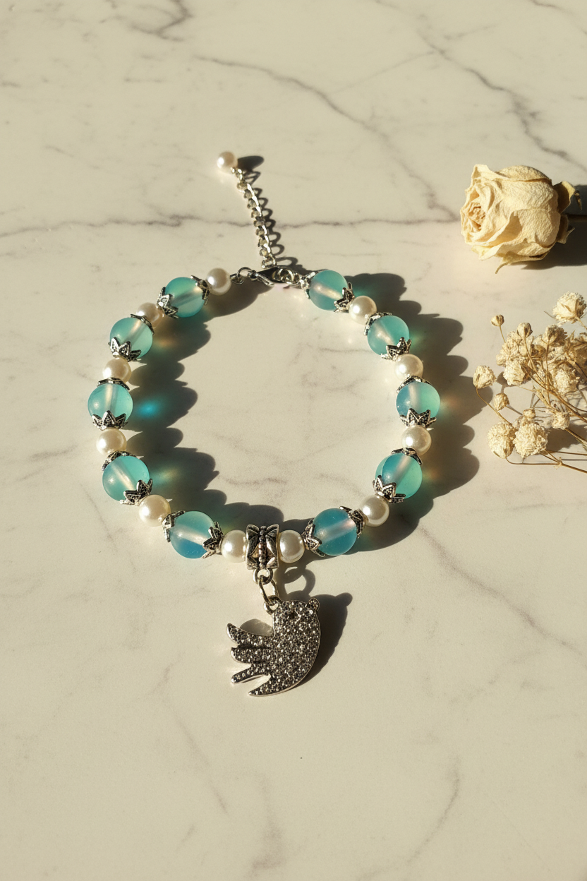 Handcrafted bead bracelet with bird charm on marble lifestyle background