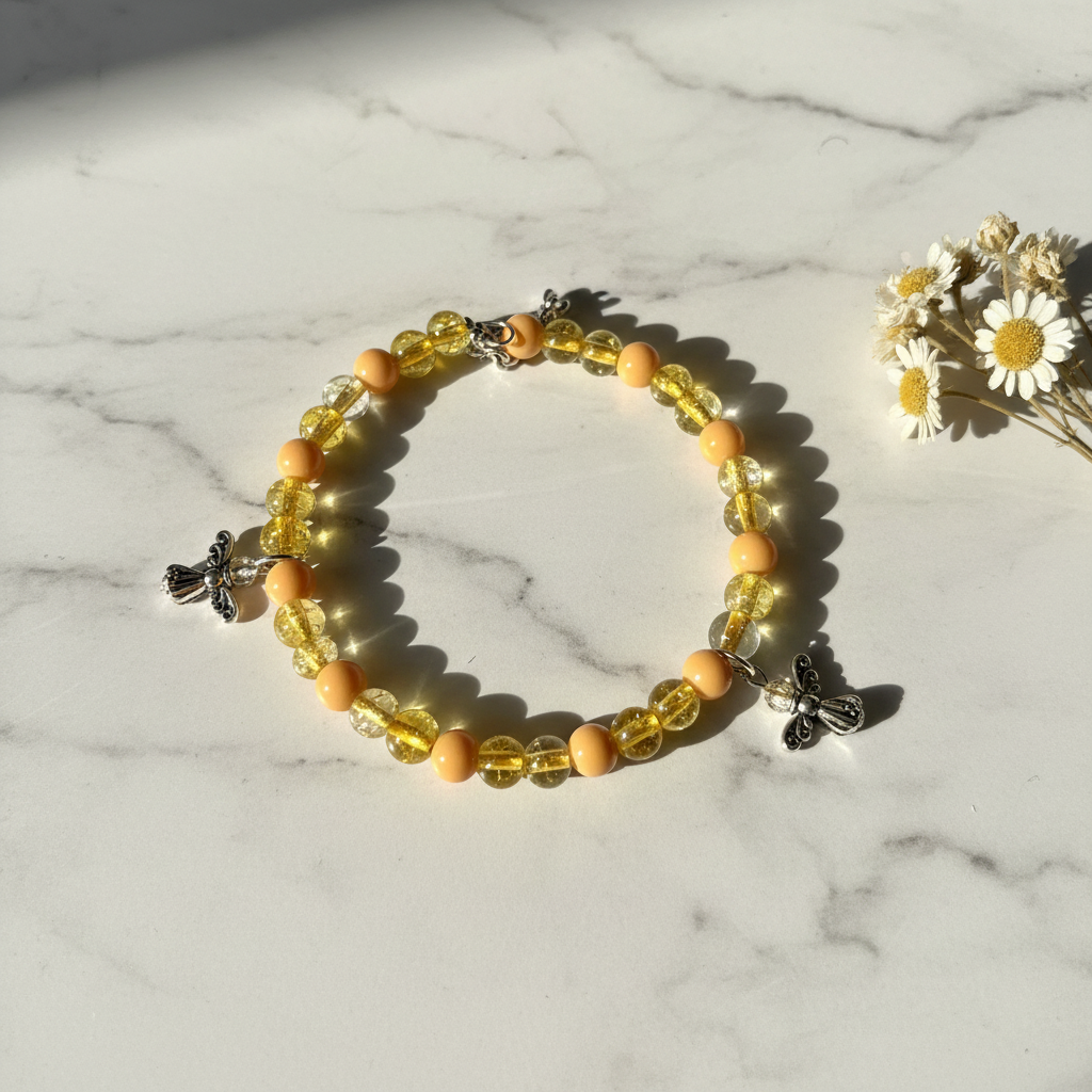 Peach and yellow crackle glass bee charm bracelet on marble lifestyle background