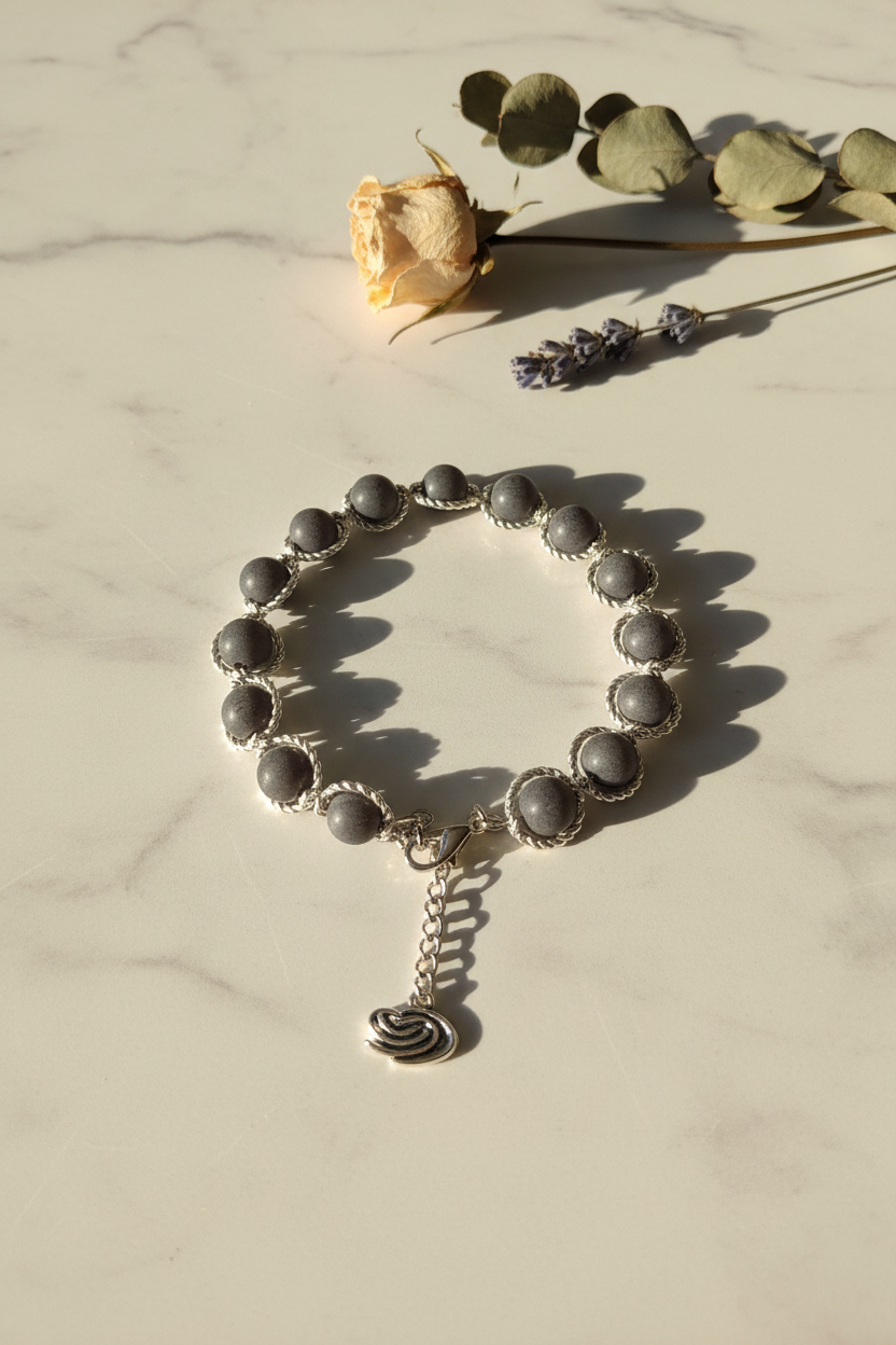 Gray glass moon bead bracelet with saturn charm on marble lifestyle background