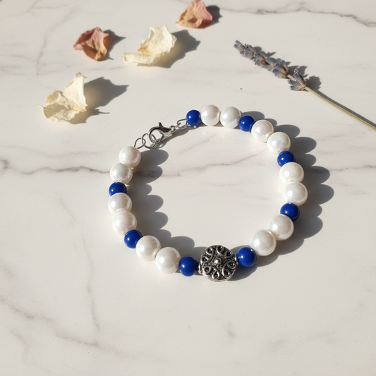 White pearl and cobalt blue bead bracelet with silver filigree focal bead on marble lifestyle background