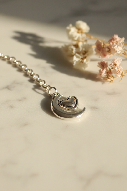 Moon and heart silver charm close-up on marble lifestyle background
