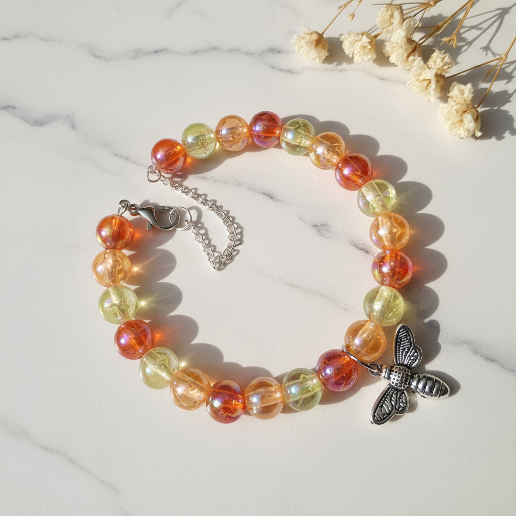 Orange and yellow iridescent bead bracelet with dragonfly charm on marble lifestyle