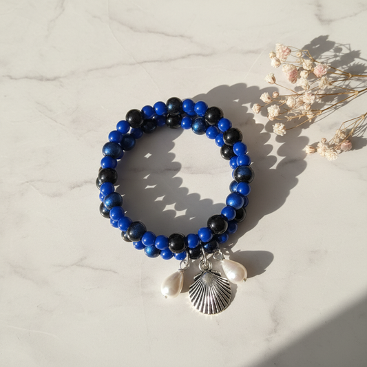 Royal blue and black memory wire wrap bracelet with Beach Girl seashell and pearl charms on marble lifestyle