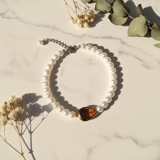 White pearl bracelet with amber teardrop focal bead on marble lifestyle